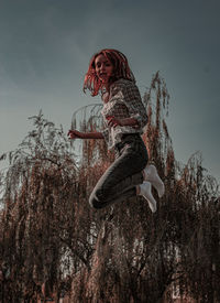 Low angle view of woman on tree against sky