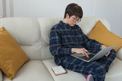 Young man using laptop while sitting on sofa at home