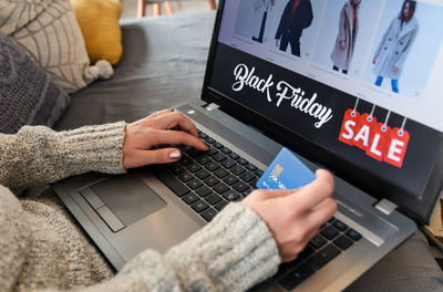 Midsection of woman using laptop while doing online shopping at home