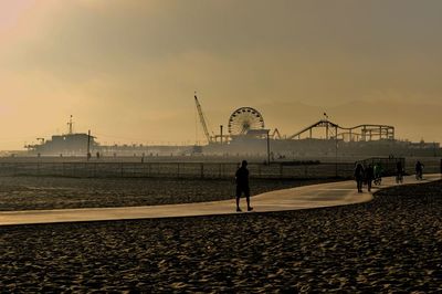 People at amusement park by sea against sky