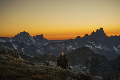 Hiker travels by headlamp on mountain ridge after sunet.