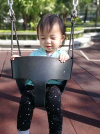 Cute girl sitting in swing at playground