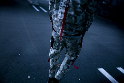 Rear view of man in camouflage clothing walking on street
