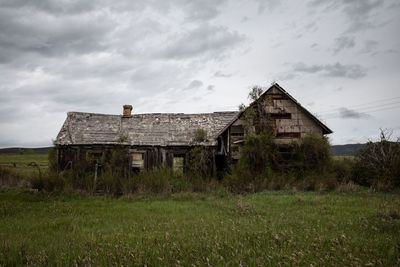 Abandoned house on field against sky