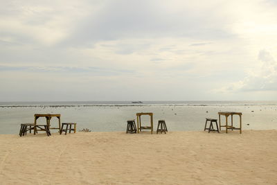 Chairs and table on beach against sky