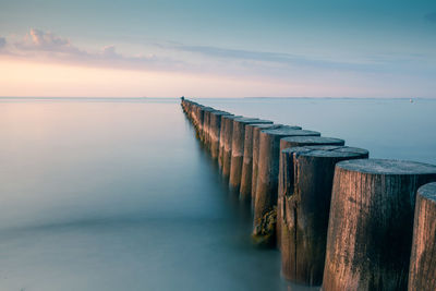 Wooden posts on pier over sea against sky