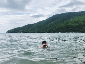 Man swimming in sea against sky