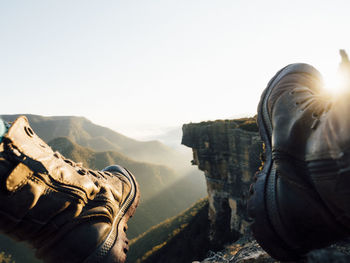 Low section of man on cliff against clear sky