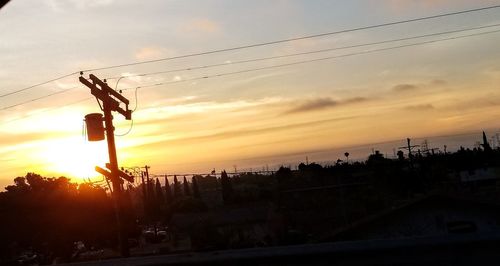 Silhouette electricity pylon against sky during sunset