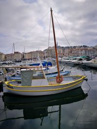 Boats moored at harbor against sky