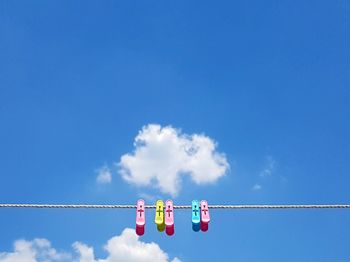 Low angle view of flags hanging against blue sky