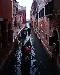 Canal amidst illuminated city against sky