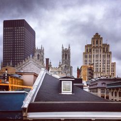 Buildings in city against cloudy sky