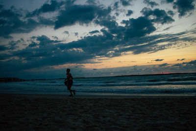 Man on beach against sky during sunset