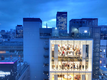 Modern buildings in city against blue sky at dusk