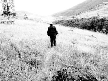 Full length rear view of man walking on field