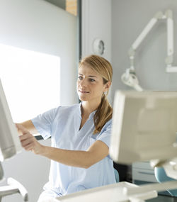 Smiling blond dentist working at dental clinic