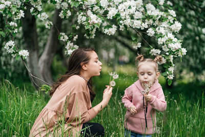 Mother and daughter with dandelions blooming apple trees