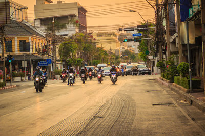 People riding motorcycles on city street during sunset