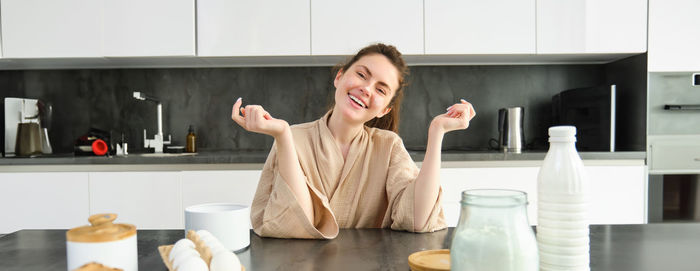 Portrait of young woman sitting in kitchen