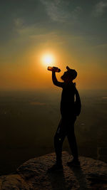 Silhouette man standing against orange sky during sunset