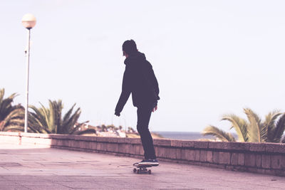 Man skateboarding on street against sky