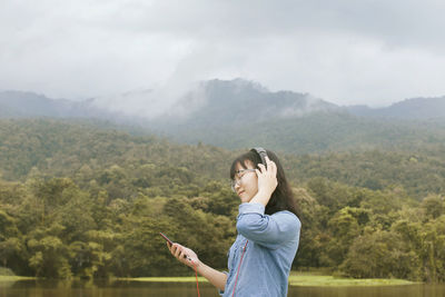 Young woman using mobile phone against mountains