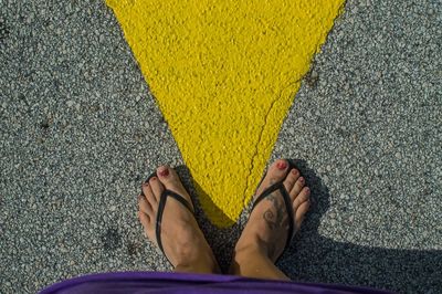 Low section of woman wearing slippers standing on road