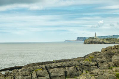 Lighthouse by sea against sky