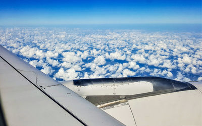 Airplane flying over clouds against blue sky