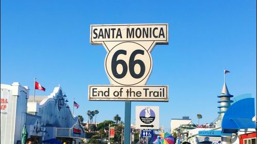 Low angle view of sign board against clear blue sky
