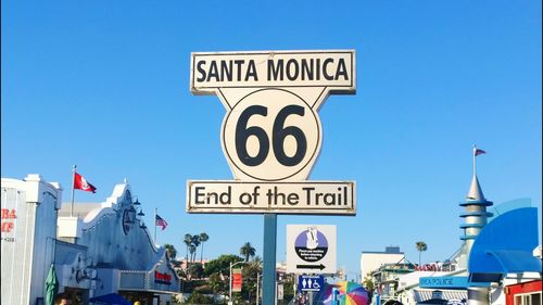 Low angle view of sign board against clear blue sky