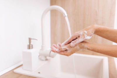 Cropped hand washing hands in bathroom