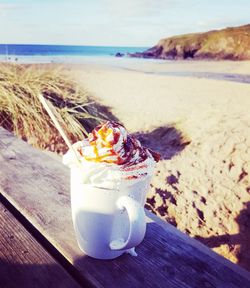 Close-up of drink at beach against sky