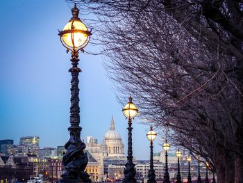 Illuminated street light and trees against clear sky