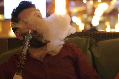 Man smoking hookah while sitting at restaurant