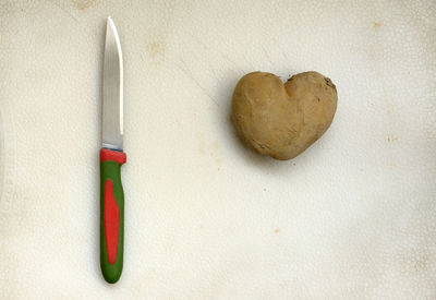 Close-up of knife with heart shape potato on table