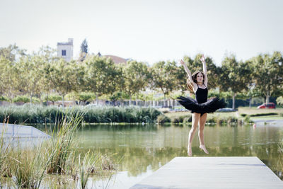 Woman ballet dancing on pier over lake