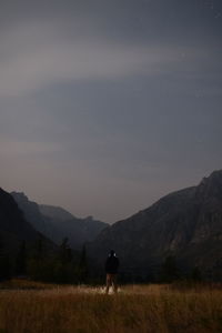 Rear view of silhouette man walking on mountain against sky