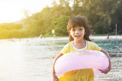 Portrait of smiling girl in inflatable ring at beach during sunny day