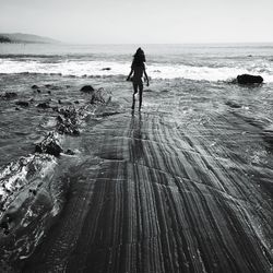 Rear view of girl walking at beach