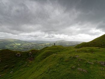 Distant view of person standing on mountain against sky