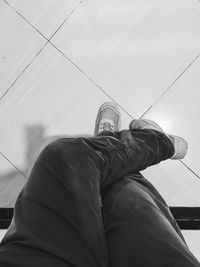 Low section of person wearing canvas shoes on tiled floor