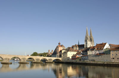 Arch bridge over river amidst buildings against sky in city