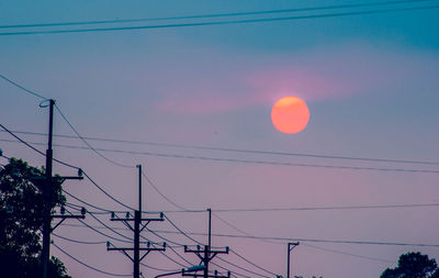 Low angle view of silhouette electricity pylon against sky during sunset