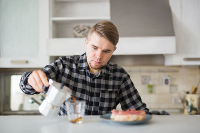 Side view of young woman drinking water at home