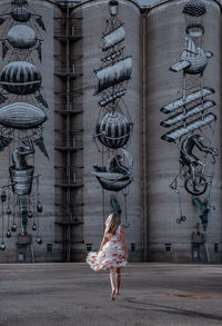 Rear view of woman dancing on street in city