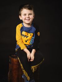 Portrait of cute baby girl sitting against black background