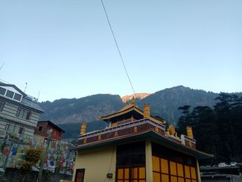 Low angle view of buildings and mountains against clear blue sky