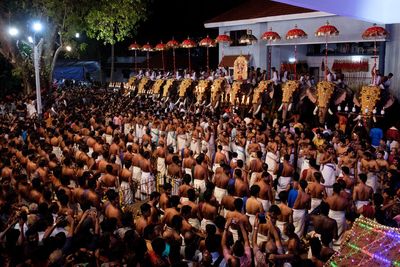 High angle view of crowd with decorated elephants in city at night during celebration